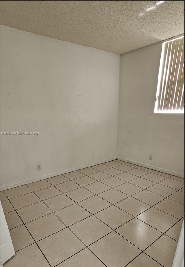 empty room featuring light tile patterned floors and a textured ceiling