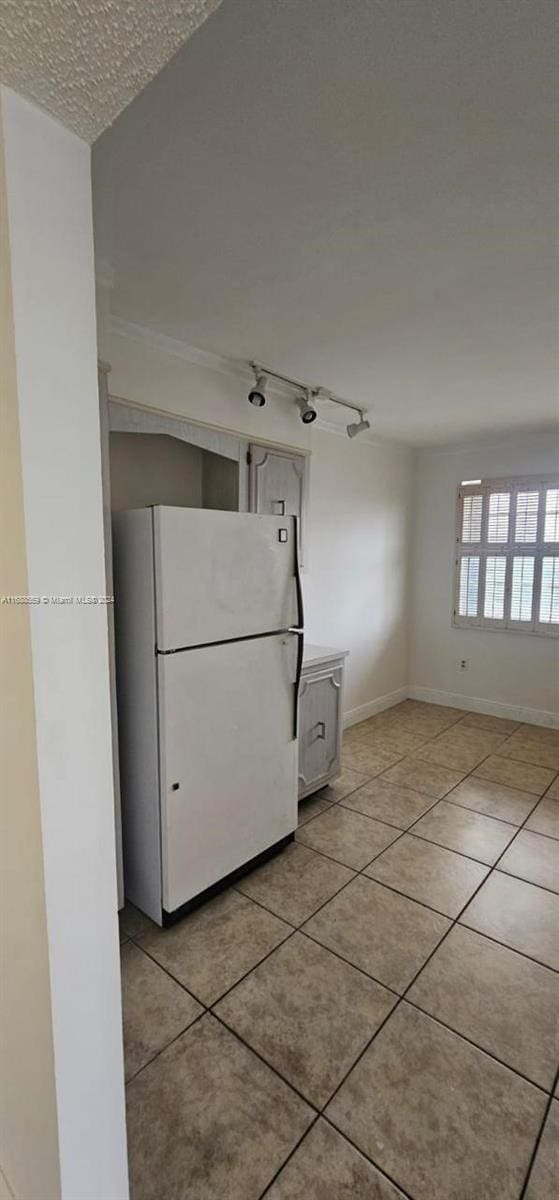 kitchen featuring white refrigerator, a textured ceiling, and light tile patterned floors