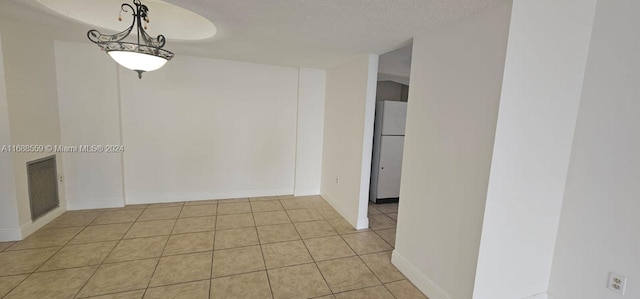 tiled spare room featuring a textured ceiling