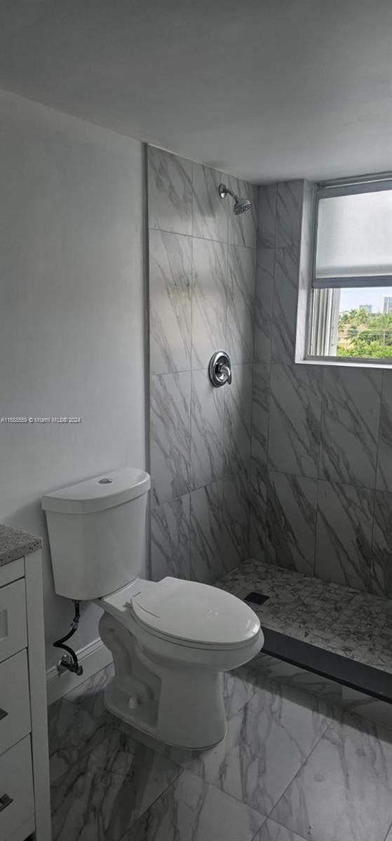 bathroom with toilet, vanity, and a tile shower