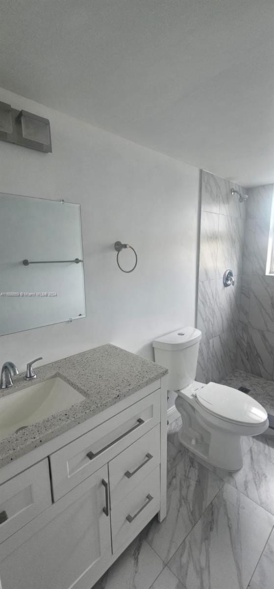 bathroom featuring vanity, toilet, and a tile shower