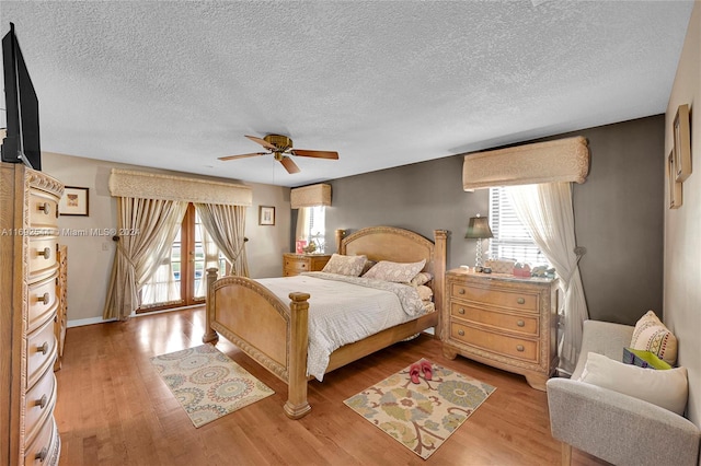 bedroom with light hardwood / wood-style flooring, a textured ceiling, ceiling fan, and access to exterior