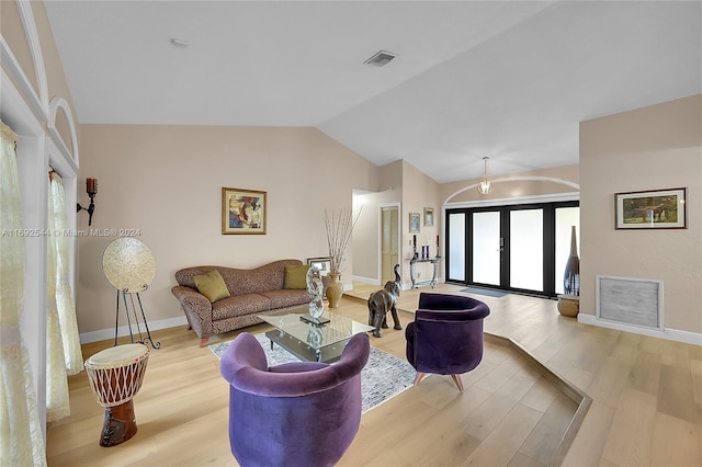 living room with light hardwood / wood-style floors, french doors, and vaulted ceiling