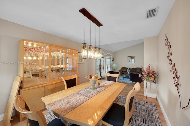 dining room featuring a notable chandelier, wood-type flooring, and vaulted ceiling