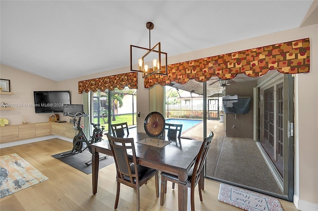 dining room with hardwood / wood-style floors, lofted ceiling, and an inviting chandelier