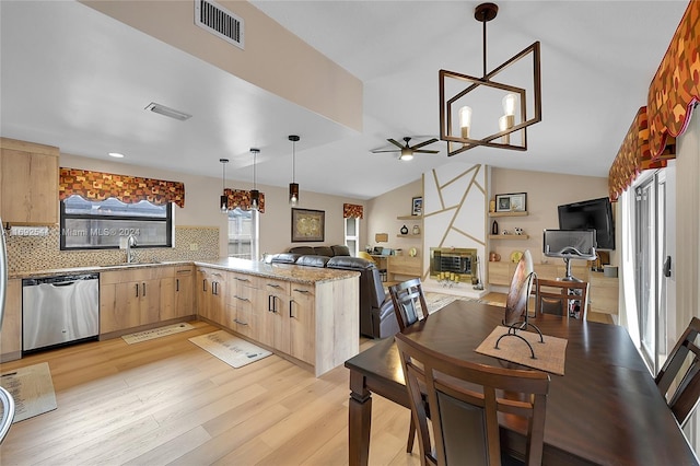 kitchen with light hardwood / wood-style floors, kitchen peninsula, light brown cabinetry, dishwasher, and vaulted ceiling