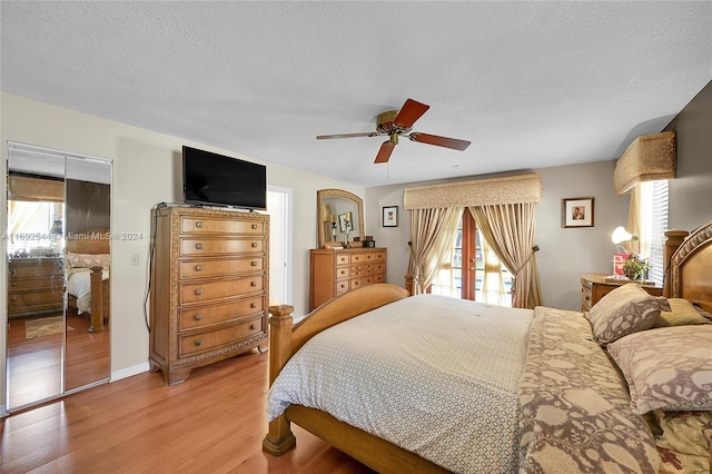 bedroom with light hardwood / wood-style floors, ceiling fan, and a textured ceiling