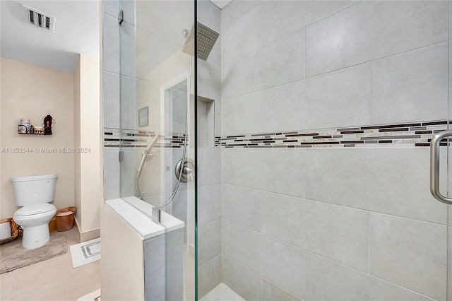 bathroom featuring toilet, tile patterned floors, and a shower with door