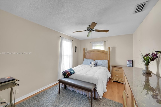 bedroom with a textured ceiling, light hardwood / wood-style flooring, and ceiling fan