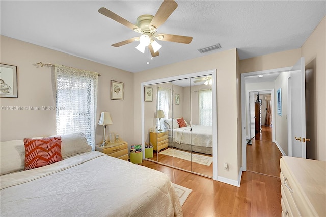 bedroom featuring a closet, wood-type flooring, ceiling fan, and a textured ceiling