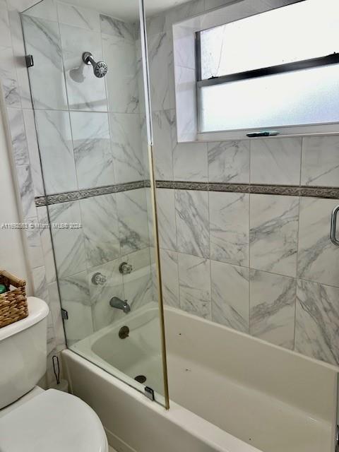 bathroom with toilet and tiled shower / bath