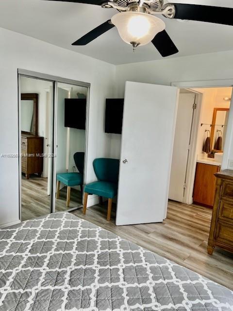 bedroom with hardwood / wood-style floors, ceiling fan, ensuite bath, and a closet