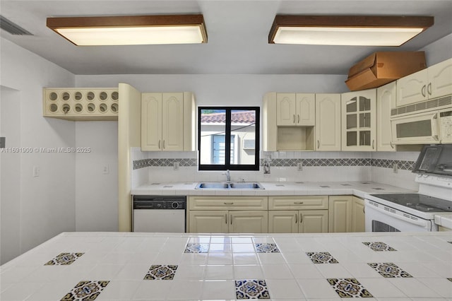 kitchen with sink, white appliances, tile countertops, and decorative backsplash