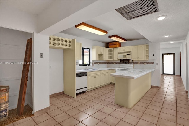 kitchen with sink, light tile patterned floors, tile counters, white appliances, and decorative backsplash