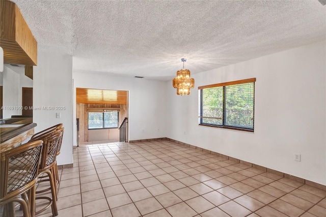 interior space featuring light tile patterned floors, a textured ceiling, and a chandelier