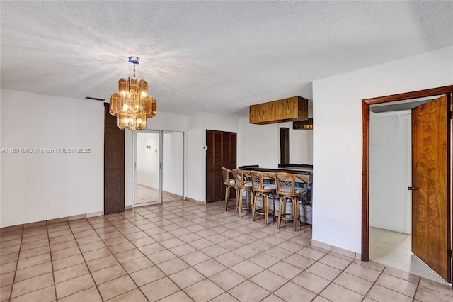 kitchen featuring a barn door, light tile patterned floors, a notable chandelier, and a textured ceiling