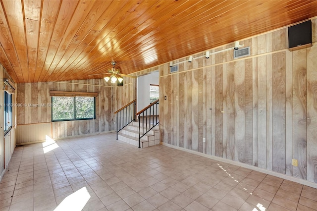 tiled empty room with lofted ceiling, wood ceiling, wooden walls, and ceiling fan