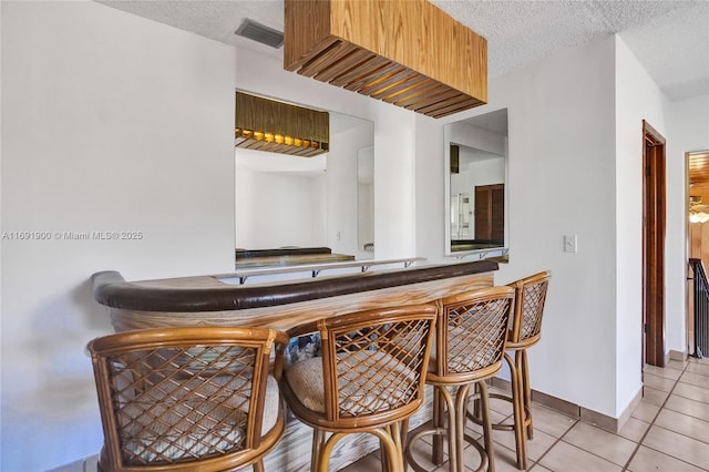 bar with light tile patterned floors and a textured ceiling