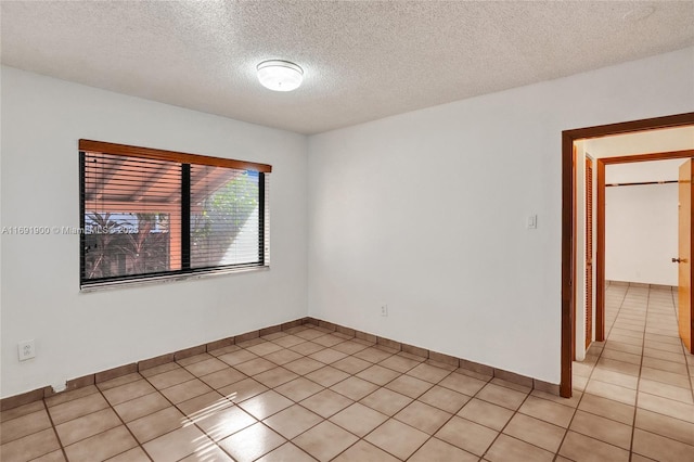 unfurnished room with light tile patterned flooring and a textured ceiling