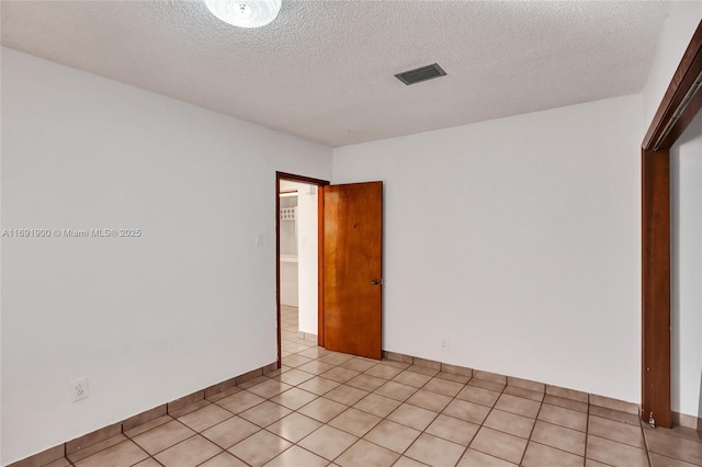 spare room with light tile patterned floors and a textured ceiling