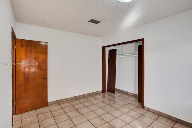 unfurnished bedroom with light tile patterned floors, a closet, and a textured ceiling