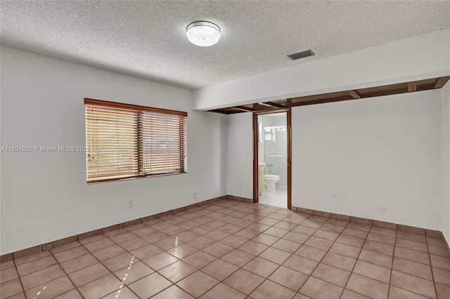 tiled spare room featuring a textured ceiling