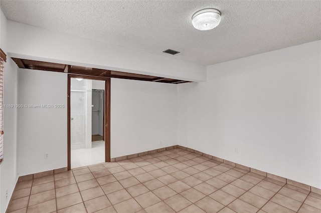 tiled empty room with a textured ceiling