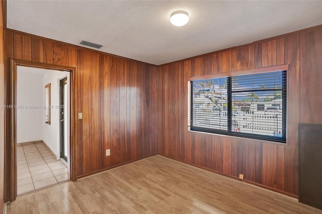 spare room featuring wooden walls and light hardwood / wood-style floors