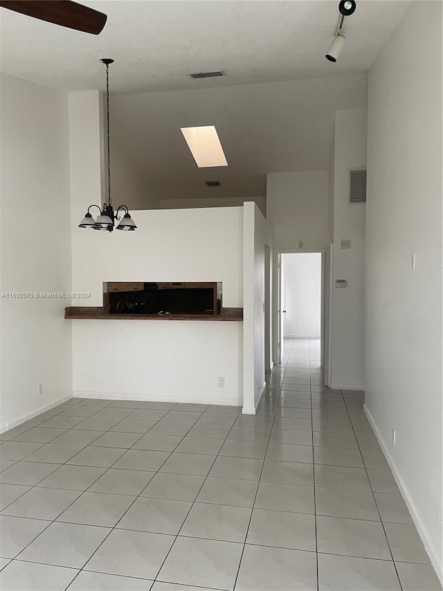 hall with a chandelier, light tile patterned floors, a textured ceiling, and a skylight