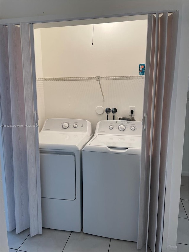 clothes washing area with washing machine and dryer and light tile patterned flooring