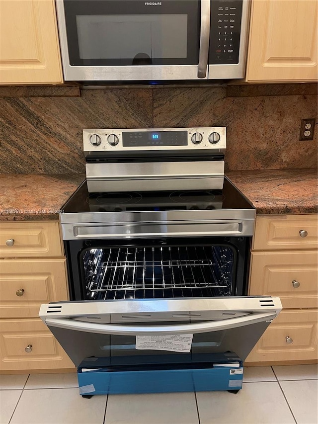 room details with decorative backsplash, appliances with stainless steel finishes, light brown cabinetry, and dark stone counters