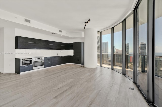 unfurnished living room featuring expansive windows and light hardwood / wood-style flooring