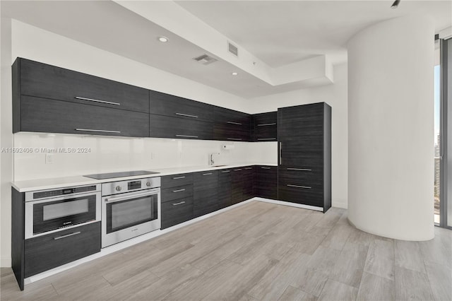 kitchen featuring stainless steel oven, light hardwood / wood-style floors, and black electric stovetop