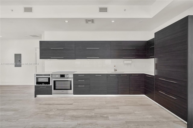 kitchen featuring dark brown cabinets, black stovetop, sink, and oven