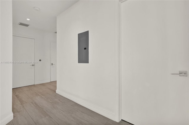 corridor with electric panel and light hardwood / wood-style flooring