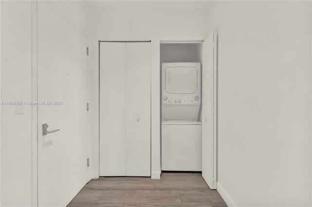 laundry area featuring light hardwood / wood-style floors and stacked washer and clothes dryer