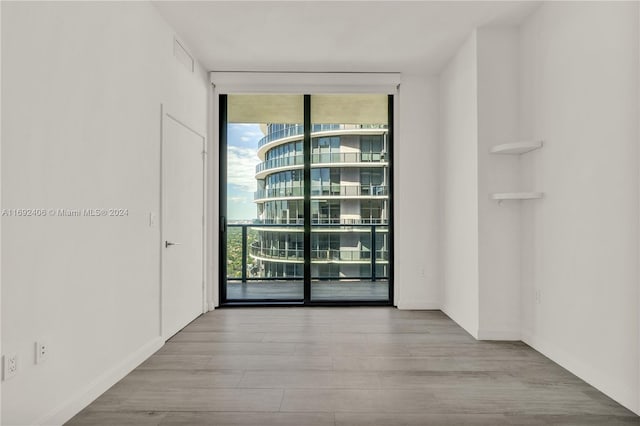 spare room featuring expansive windows and light wood-type flooring