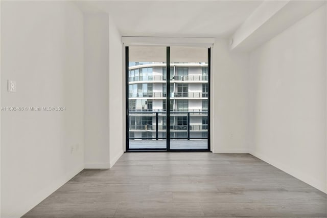 unfurnished room featuring light hardwood / wood-style floors and a wall of windows