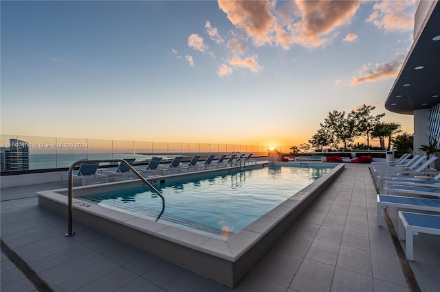 pool at dusk featuring a water view