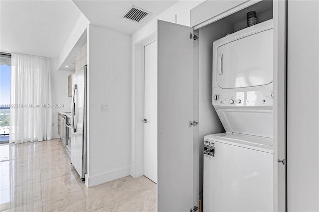 121 NE 34th St Unit 3116, Miami, FL 33137 - washroom featuring stacked washer / drying machine, light marble finish flooring, and baseboards