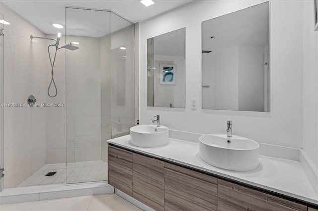 bathroom featuring tile patterned flooring, vanity, and a tile shower