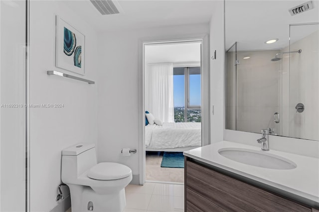 bathroom featuring vanity, a shower with door, tile patterned floors, and toilet