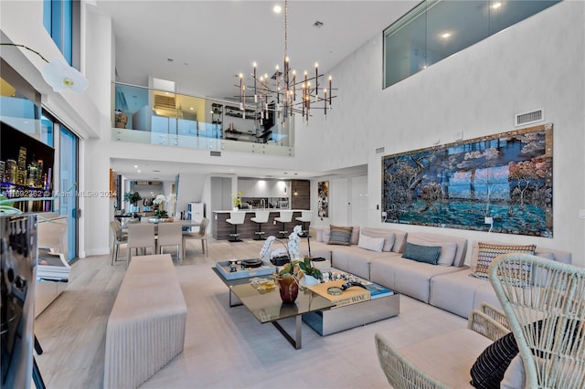 living room with a high ceiling, a chandelier, and light hardwood / wood-style floors