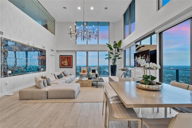 dining space featuring a chandelier, light wood-type flooring, a wealth of natural light, and a towering ceiling