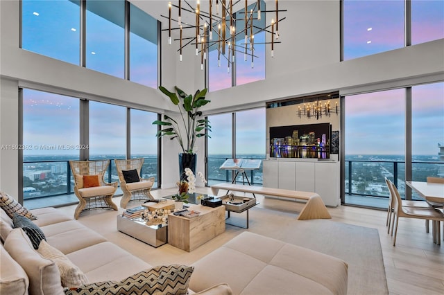 living room with a towering ceiling, plenty of natural light, a notable chandelier, and hardwood / wood-style flooring