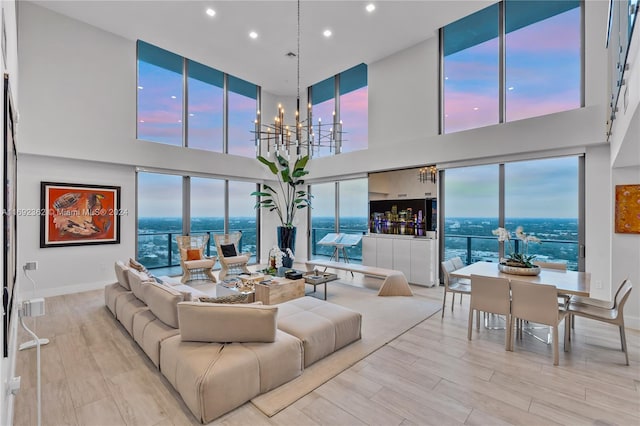 living room with a high ceiling, an inviting chandelier, and light hardwood / wood-style floors