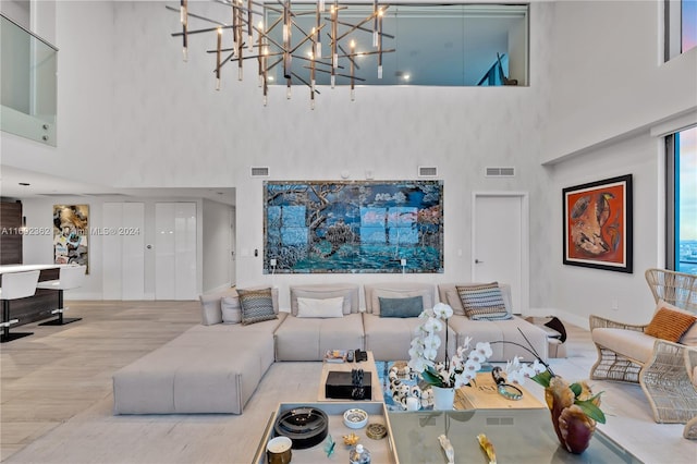 living room featuring a towering ceiling, light hardwood / wood-style flooring, and a notable chandelier