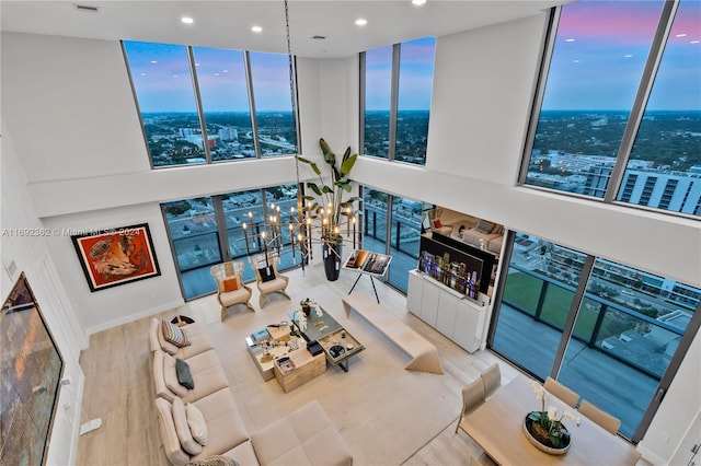 living room with a high ceiling, light wood-type flooring, and floor to ceiling windows