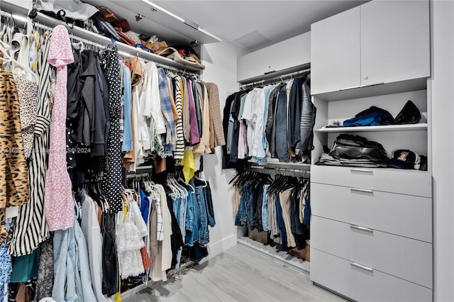 walk in closet with light hardwood / wood-style flooring