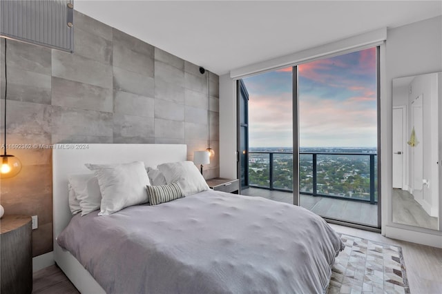 bedroom featuring access to exterior, hardwood / wood-style floors, expansive windows, and multiple windows